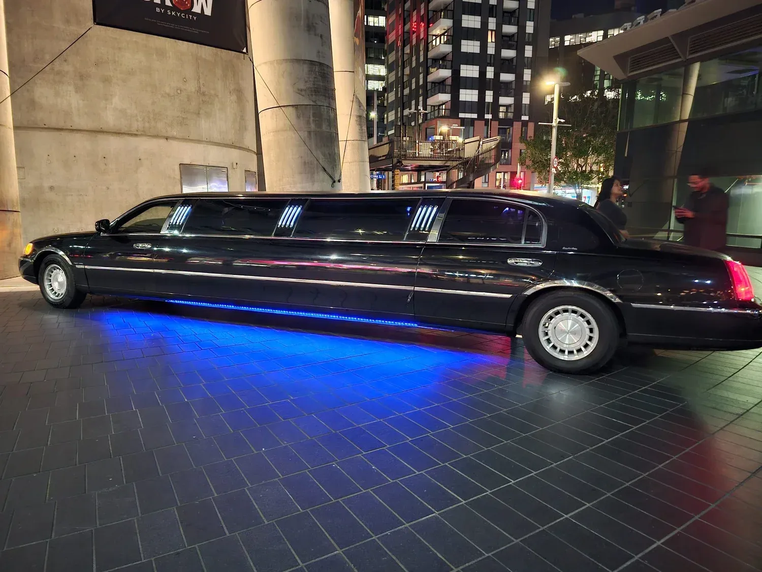 Black Lincoln stretch limousine at night in Auckland with blue underglow