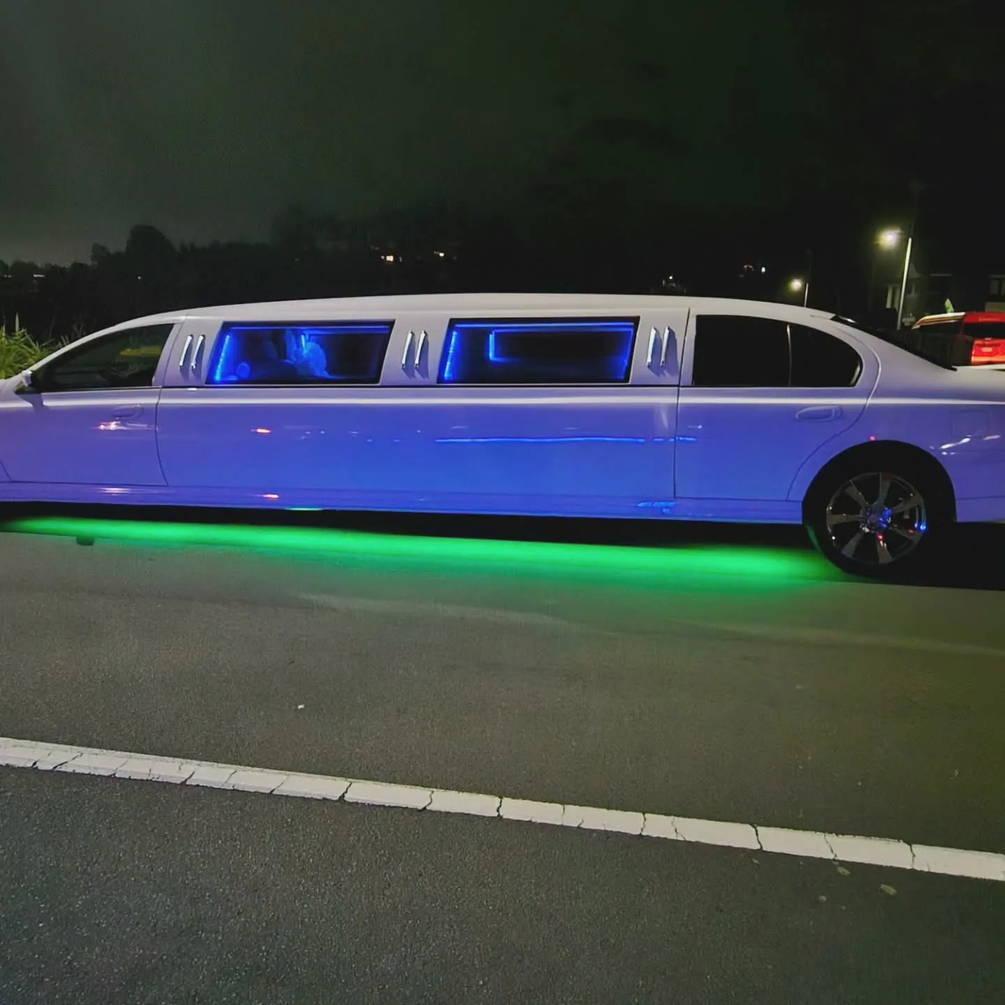 White Ford Falcon stretch limo with green LED underglow at night