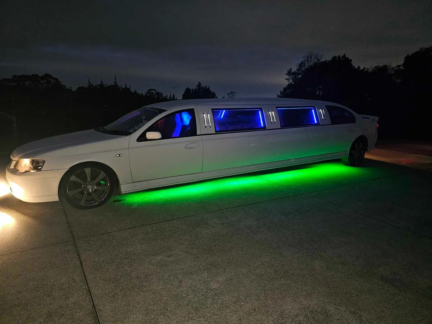 White stretch limousine at night with blue and green LED lighting